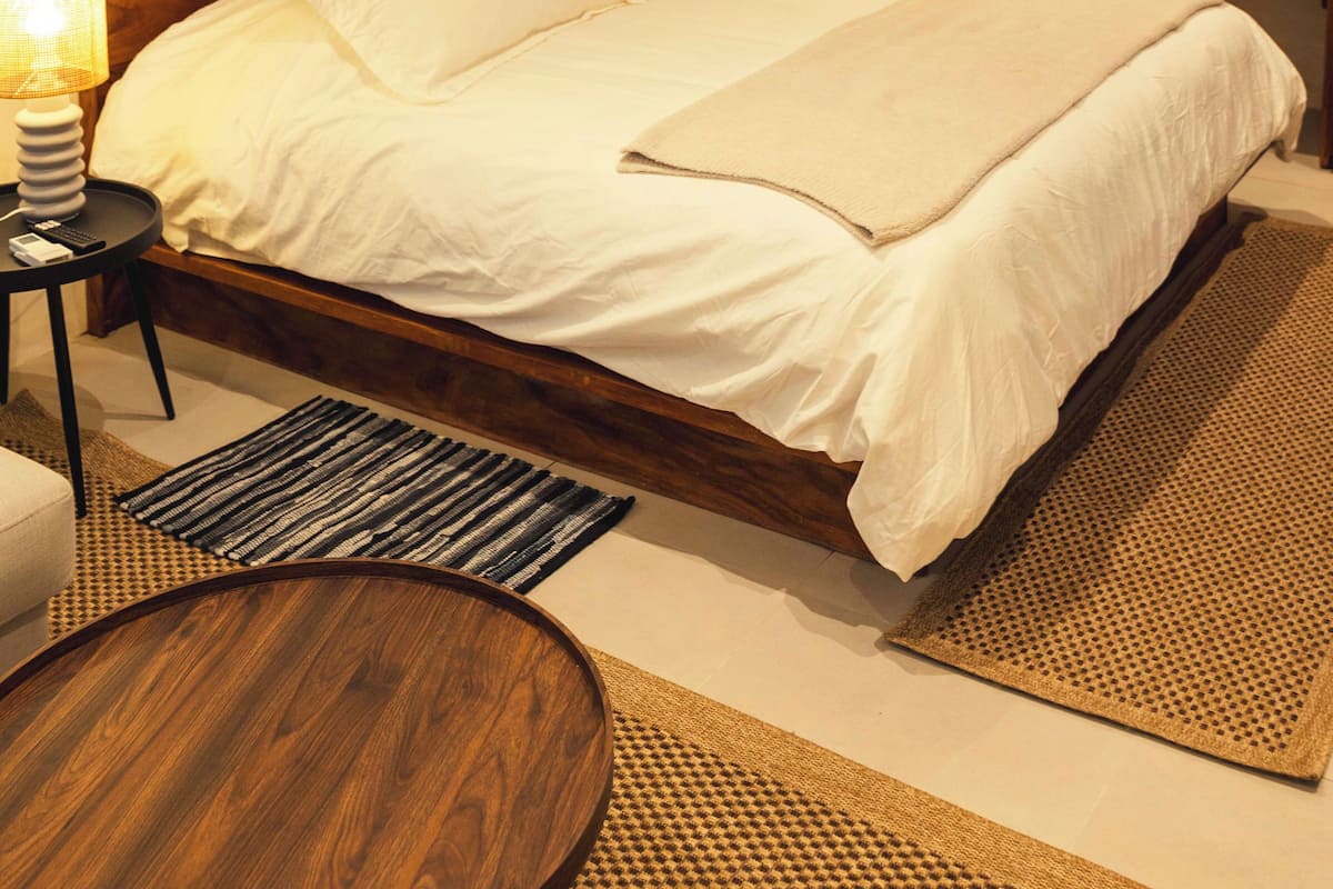 A neatly made bed with white linens, a wooden headboard, and two bedside lamps.