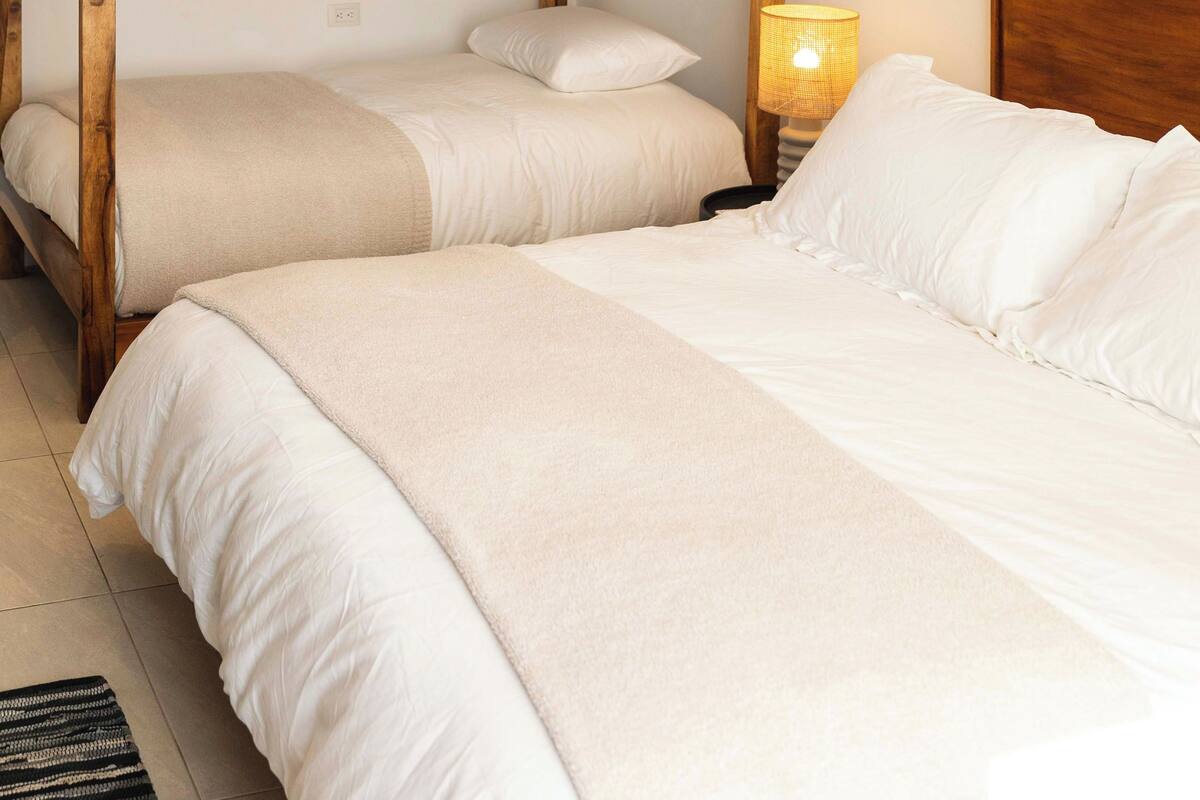 A bunk bed room with two beds, a nightstand with a lamp, and a black and white striped rug.