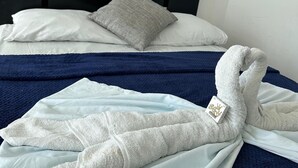 A neatly made bed with a blue blanket and a folded towel. - SGH Hotel Rodadero Suites (Santa Marta)