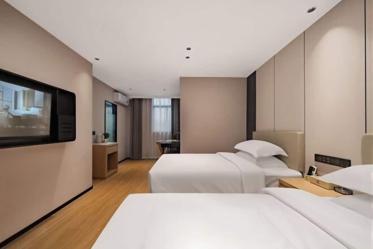 Ett hotellrum med två sängar, en TV, ett skrivbord och en stol.