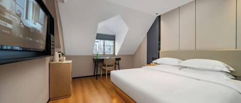 A modern hotel room with a large bed, a desk, and a television.