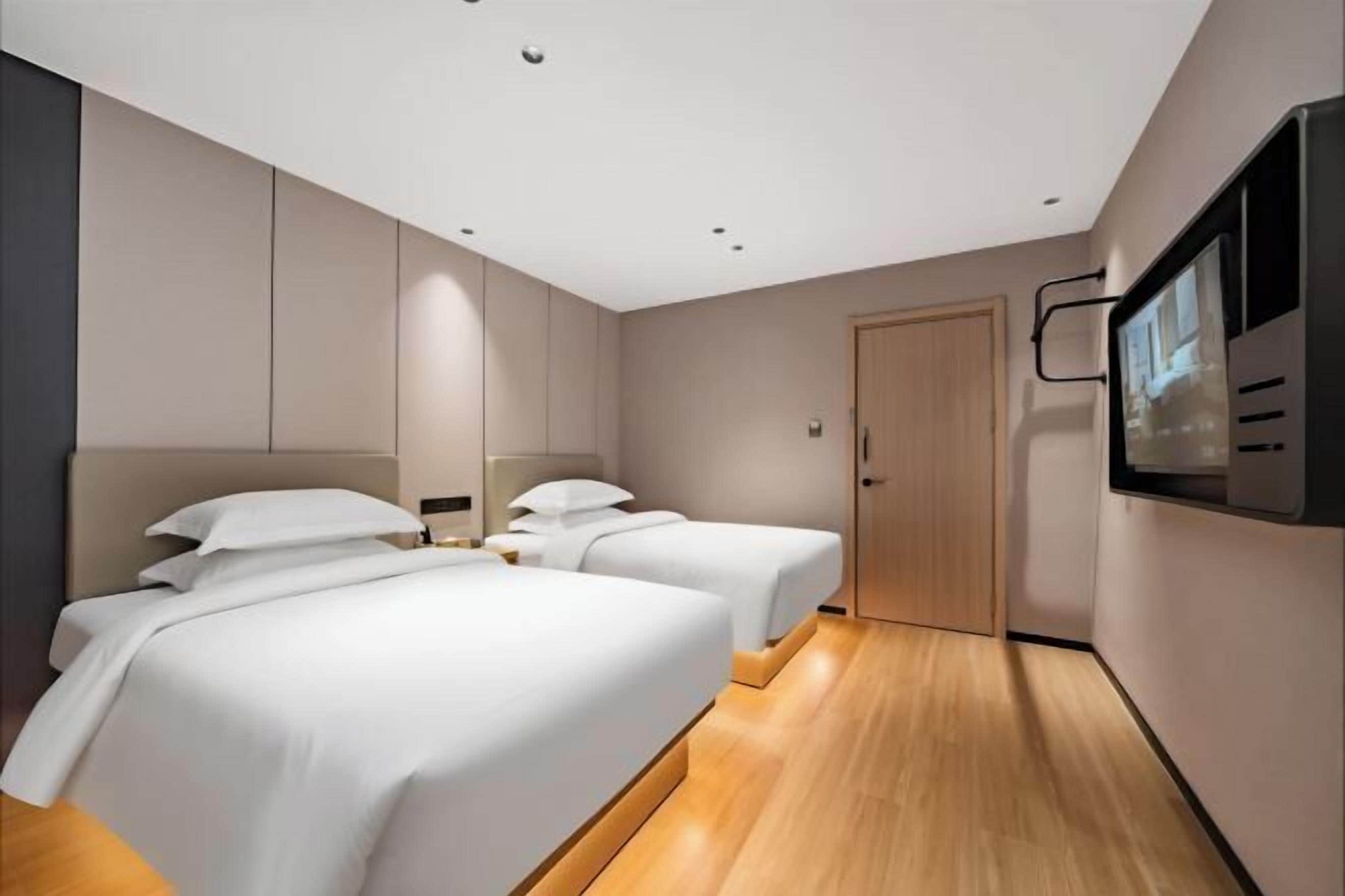 Ein Hotelzimmer mit zwei Betten, einem Fernseher und Holzboden.