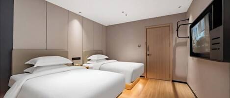 Ein Hotelzimmer mit zwei Betten, einem Fernseher und Holzboden.