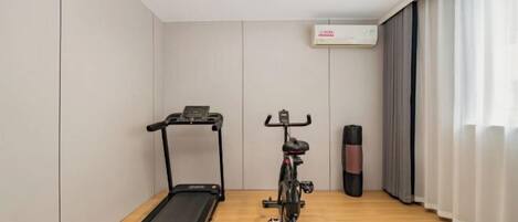 Una habitación con una cinta de correr, una bicicleta estática y un saco de boxeo.
