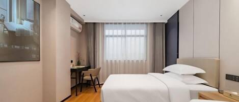 Una habitación de hotel con dos camas, un escritorio y un amplio ventanal con cortinas.