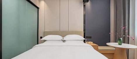 Ein modernes Hotelzimmer mit einem großen Bett, einer kleinen Sitzecke, einem runden Tisch und einer Deckenleuchte.
