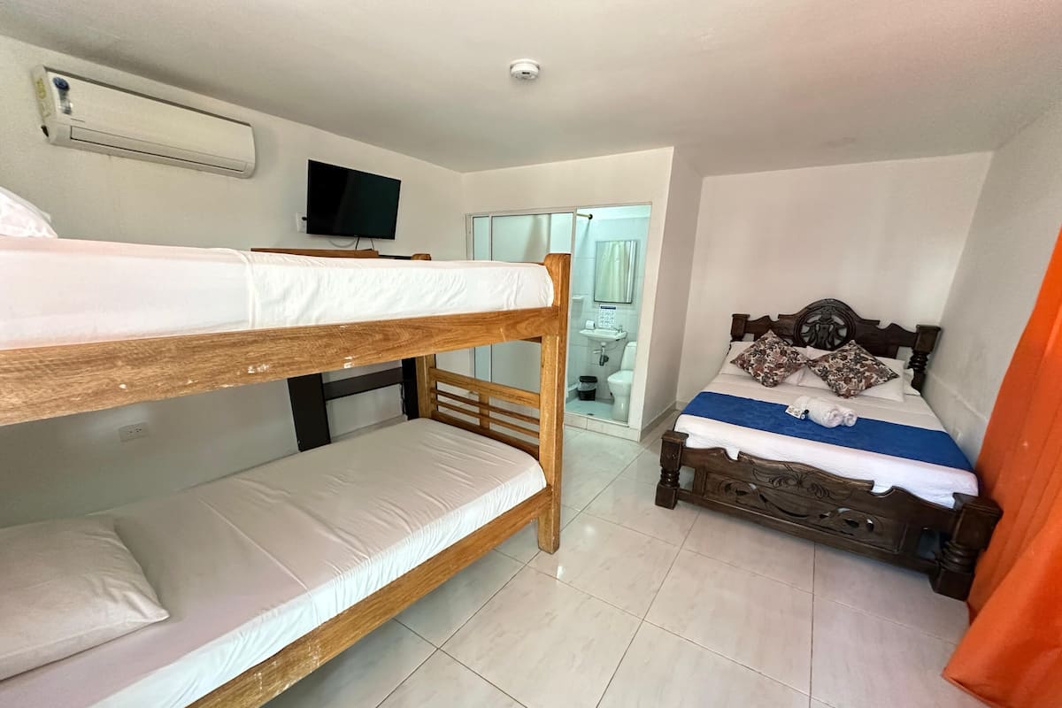 A room with bunk beds, a television, and a bathroom visible through an open door.