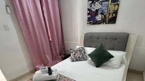 A bedroom with a bed, pillows, a blanket, a headboard, a wall-mounted air conditioner, and a poster. - Hotel Casa Mathilu (Santa Marta)