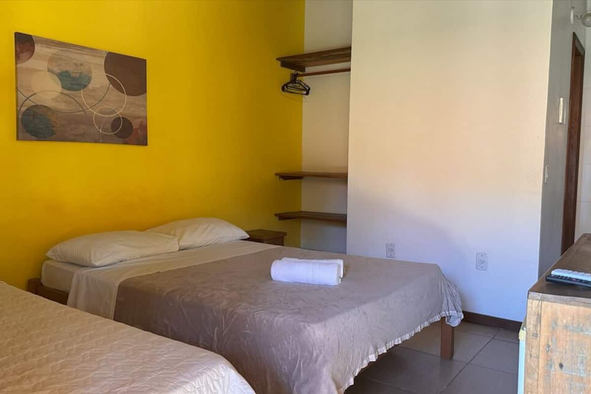 A room with two beds, a painting on the wall, and a wooden shelf unit.