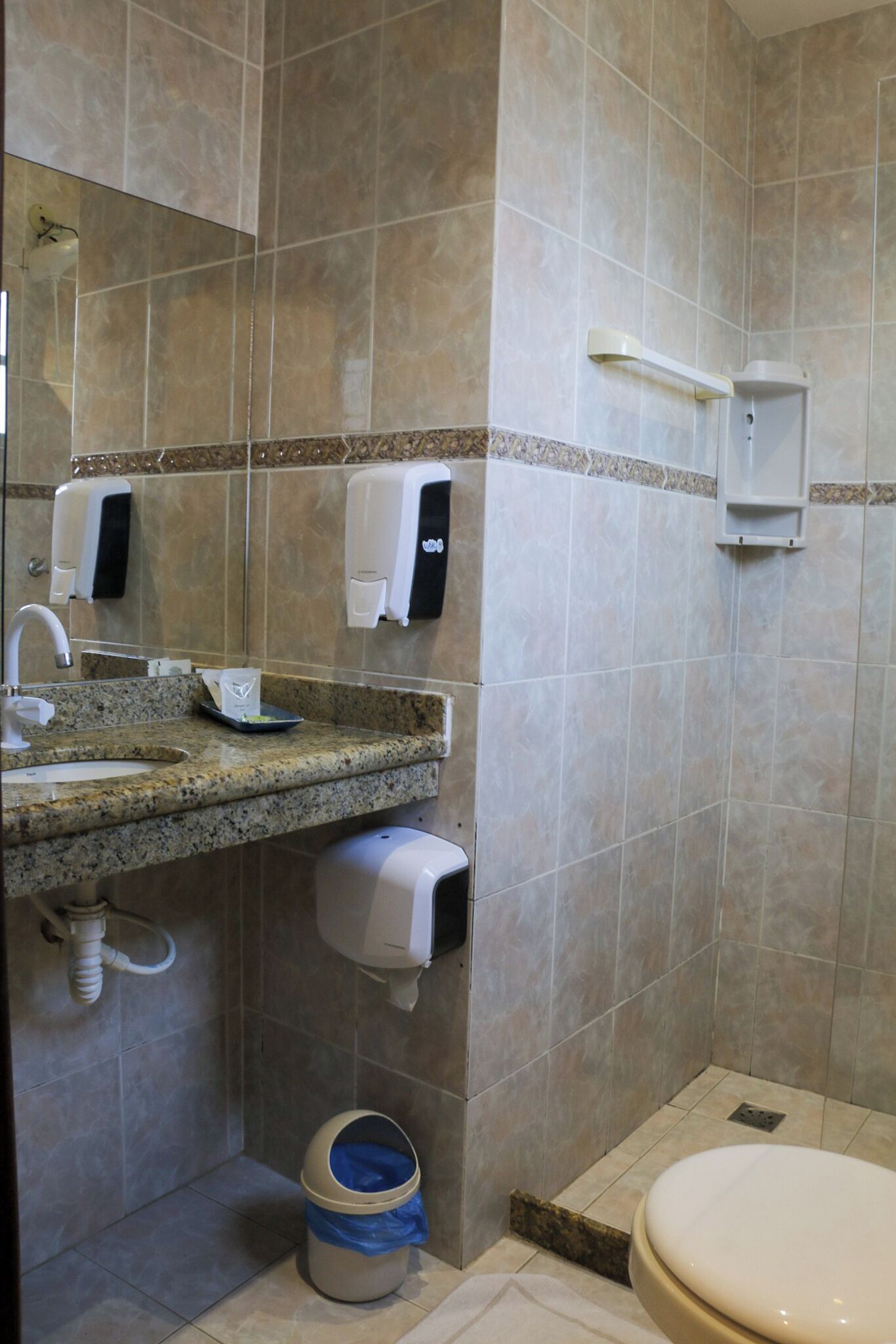 Ein Badezimmer mit Waschbecken, Spiegel, Handtrockner und Toilette.