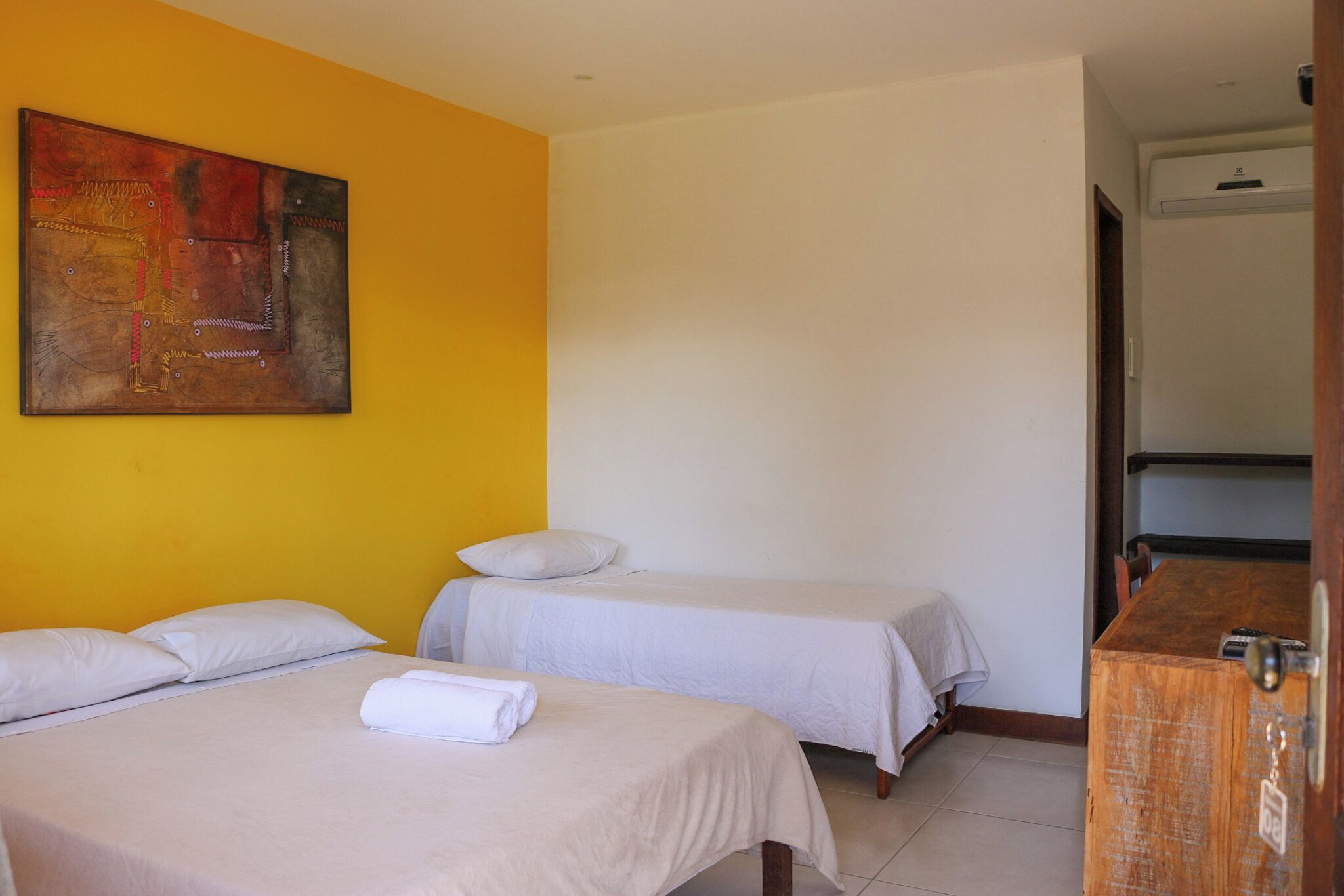 Une chambre d’hôtel avec deux lits, une commode en bois et un tableau accroché au mur.