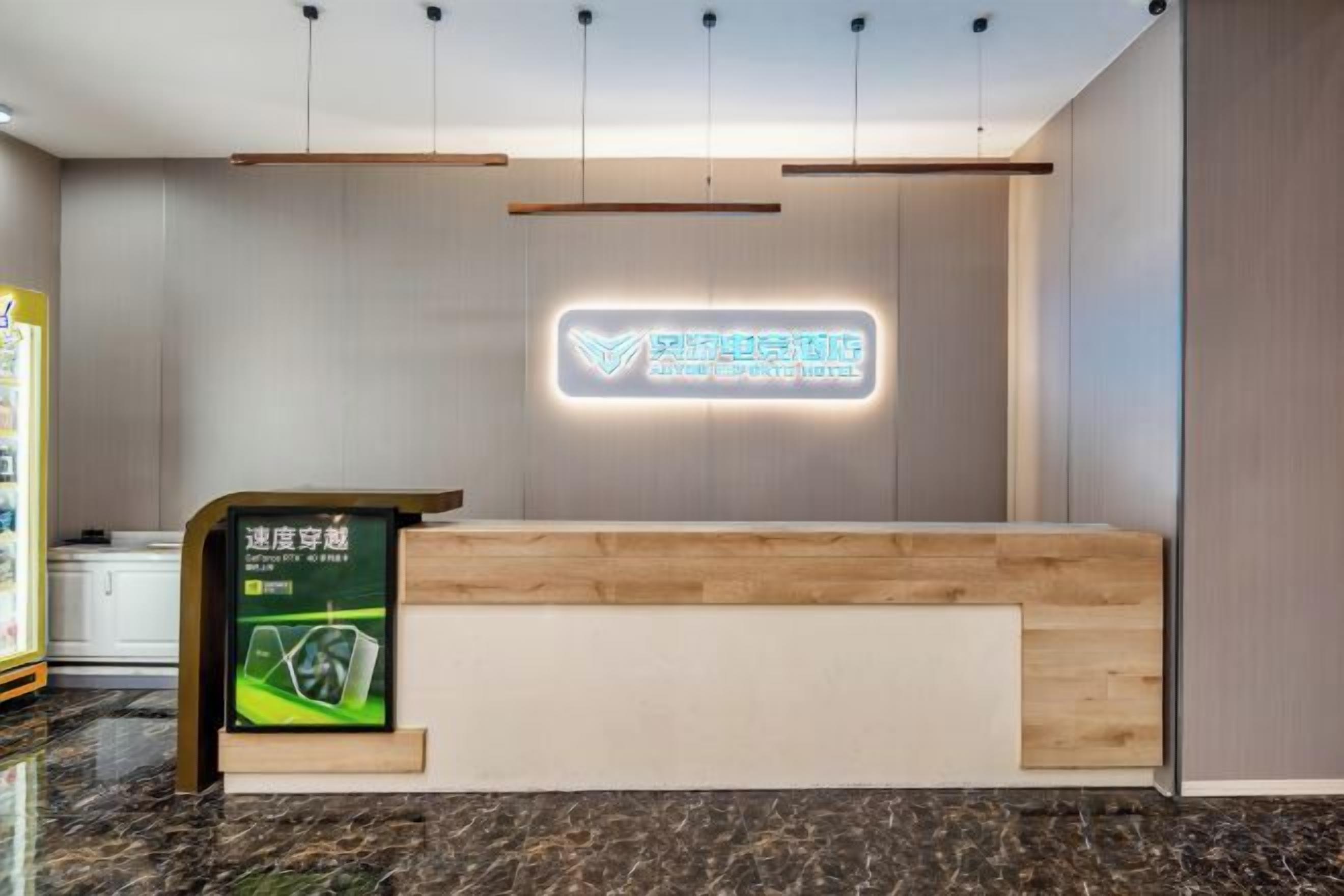 A hotel reception desk with a wooden counter, a neon sign, and a digital display.