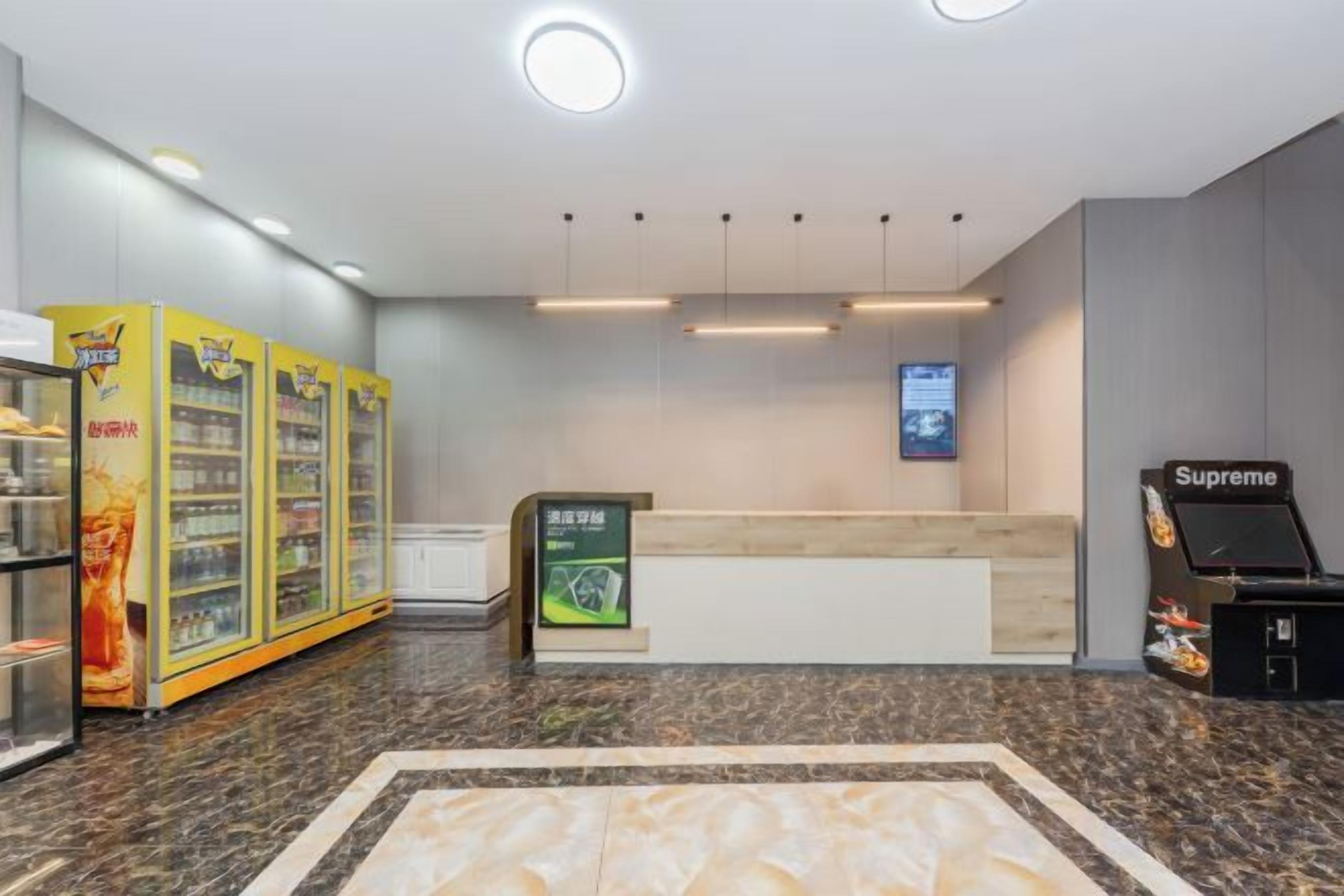 Un espace d’accueil doté d’un sol en marbre, d’un comptoir de réception, de distributeurs automatiques et d’un magasin Supreme.