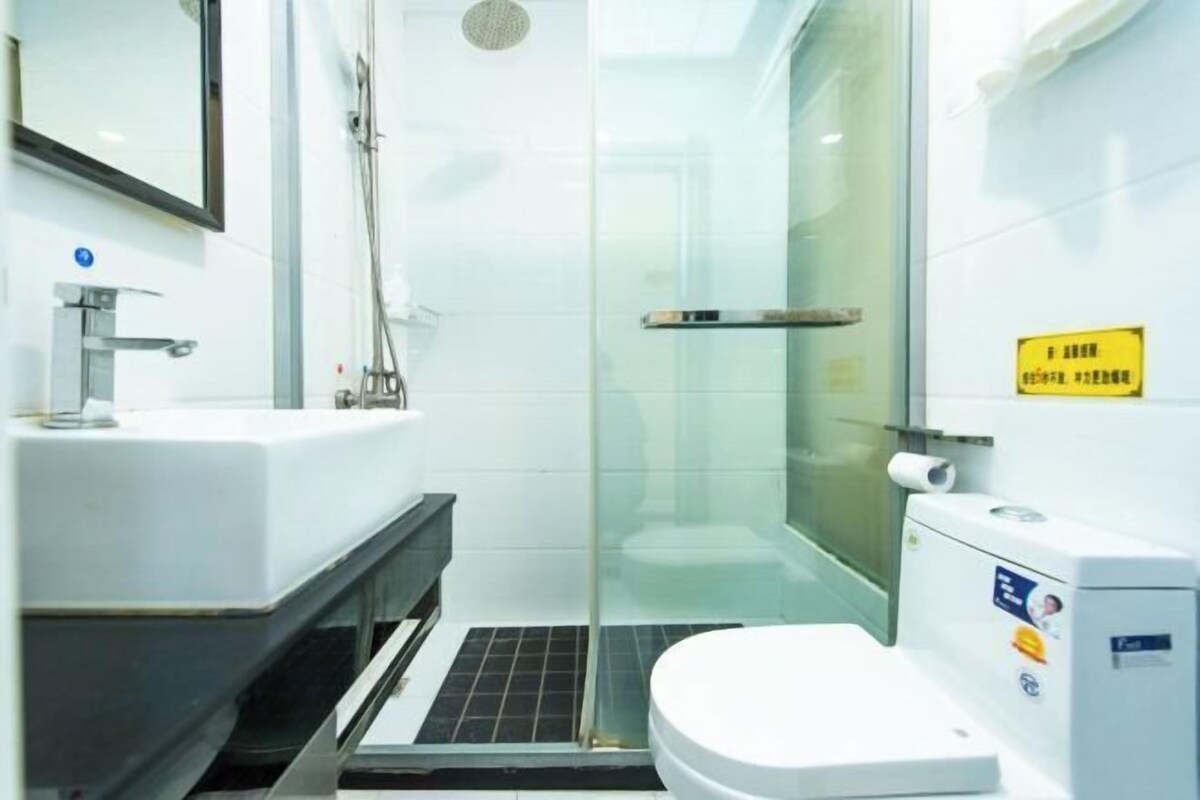 A modern bathroom with a glass-enclosed shower, a white sink, and a toilet.