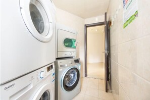 A laundry room with a front-loading washer and dryer, a wall-mounted dryer, and a door leading to another room. - Aoyou Esports Hotel (Shanghai Lujiazui) (Shanghai)