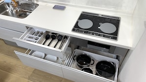 Een keuken met een ingebouwde kookplaat, een spoelbak en twee lades onder het aanrecht.