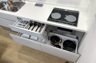 Cozinha com fogão embutido, pia e duas gavetas sob a bancada.
