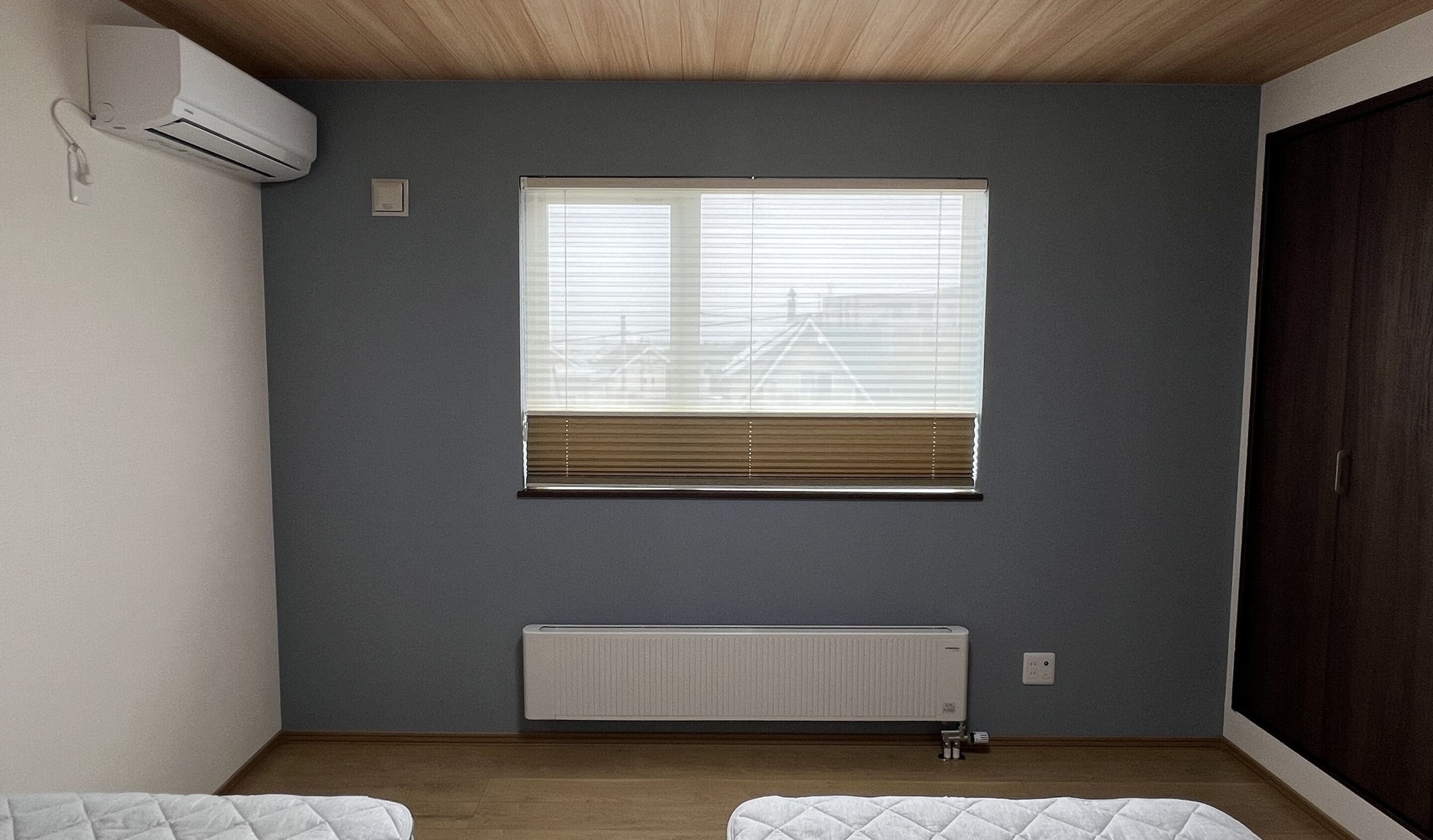 Una habitación con un ventanal grande, un radiador y un armario oscuro.
