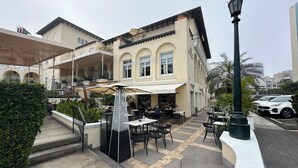 An outdoor cafe area with tables and chairs, a decorative lamp post, and a building with a balcony.
