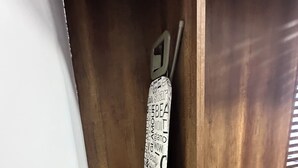 A corner of a room with a wooden floor, a metal rack, and a white object with black text.