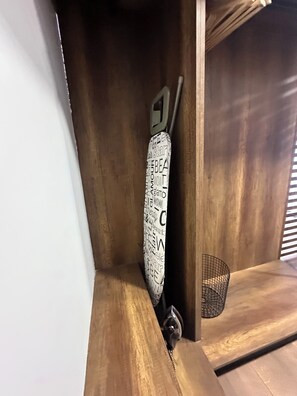 Un coin de pièce avec un plancher en bois, un présentoir métallique et un objet blanc portant une inscription noire.