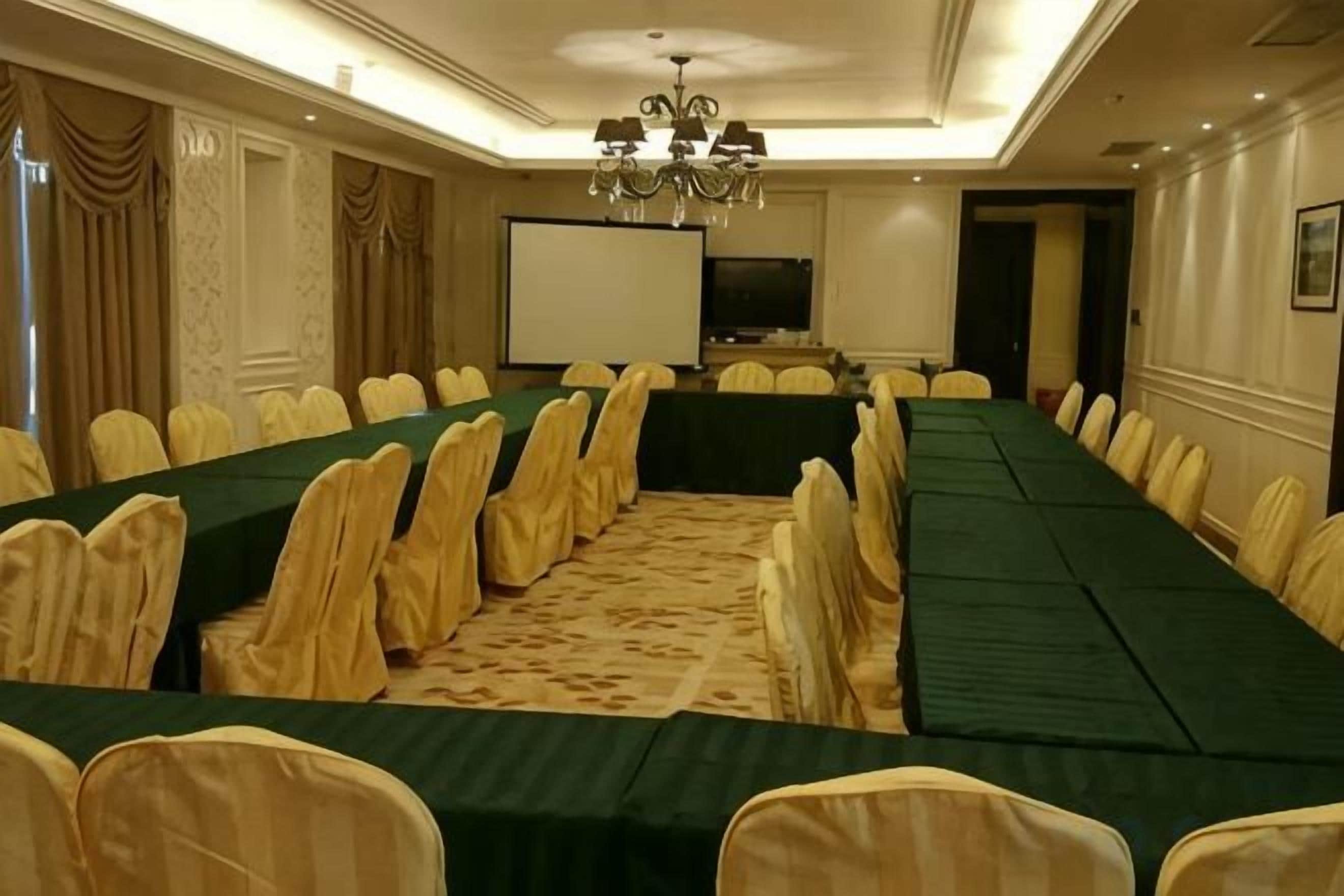 A conference room with a long table, chairs, and a projector screen.