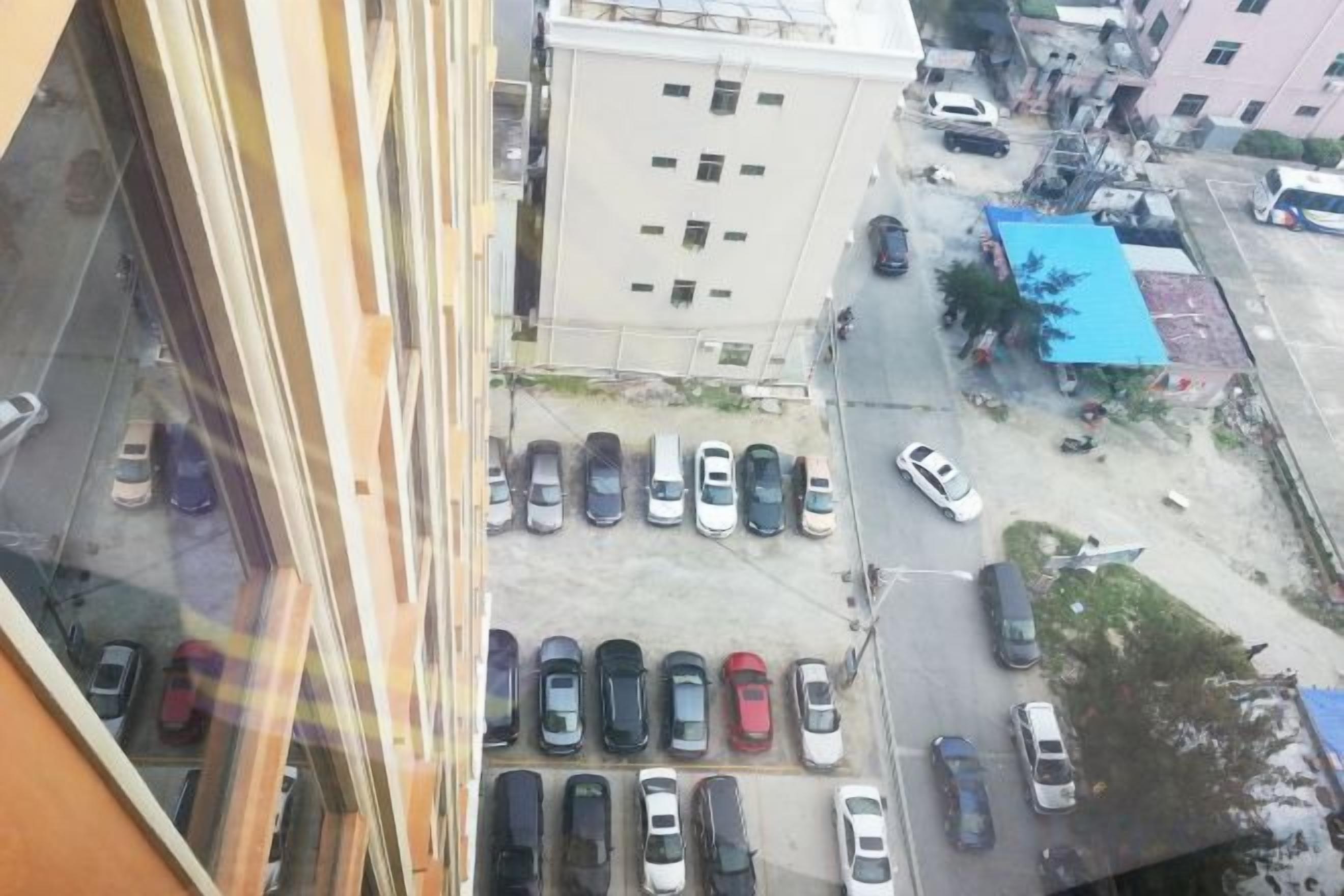 A parking lot with multiple cars, a building with a blue roof, and a clear view of the street.