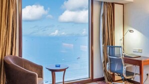 A hotel room with a large window, a desk, a chair, and a small table. - Haibaina Hotel (Huidong)