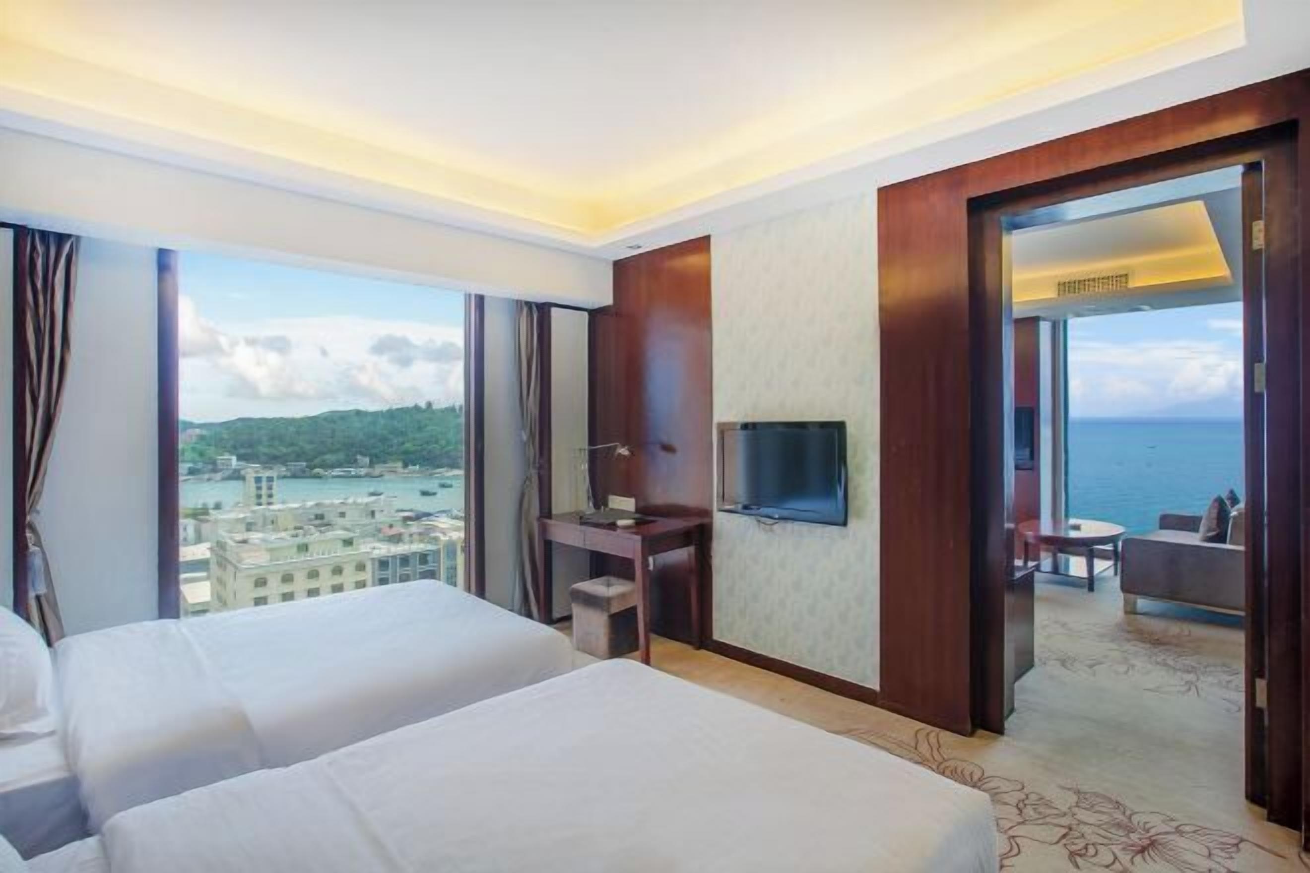 Quarto de hotel com duas camas, televisão e vista para o mar.