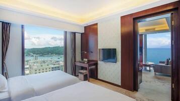 Quarto de hotel com duas camas, televisão e vista para o mar.