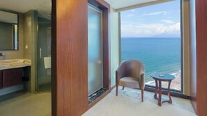A modern bathroom with a large mirror, a glass shower enclosure, and a view of the ocean through a large window. - Haibaina Hotel (Huidong)