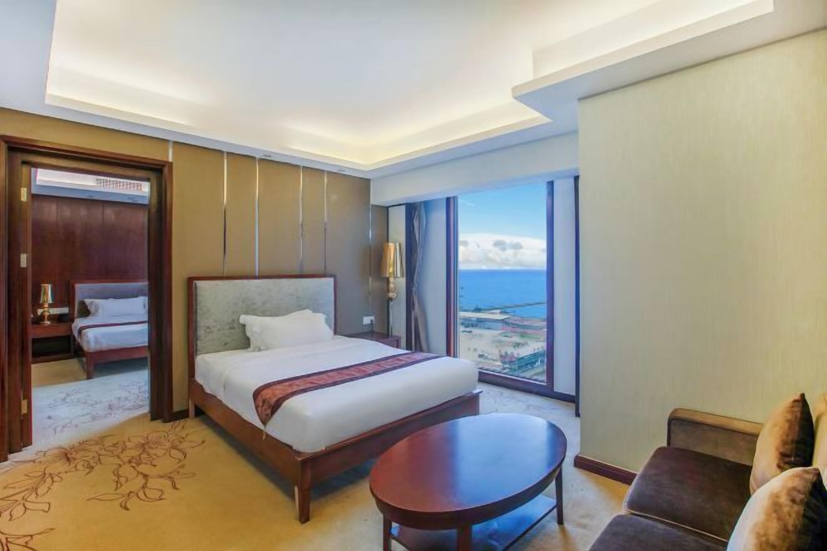 Habitación de hotel con una cama grande, una mesita, un sofá y vistas al océano.