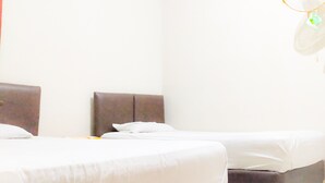 A hotel room with two beds, a red accent wall, and a small window.