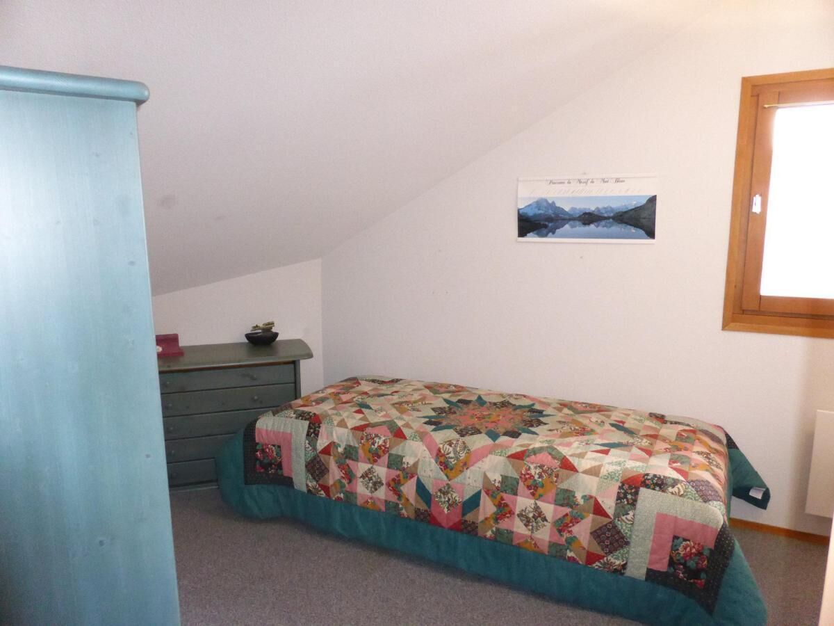 A bedroom with a bed, a dresser, and a picture on the wall.