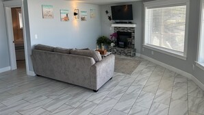 A living room with a grey sectional sofa, a fireplace, and artwork on the wall. - Luxury beachfront property with amazing views,  hot tub and steps to the beach.  (Lincoln Beach)