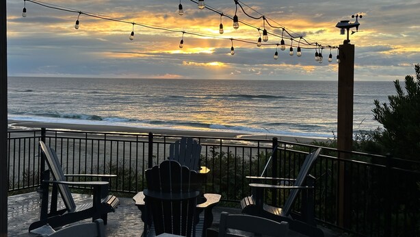 A seaside patio with chairs and tables, overlooking the ocean. - Luxury beachfront property with amazing views,  hot tub and steps to the beach.  (Lincoln Beach)