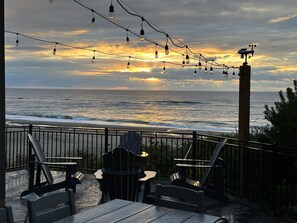 Un patio frente al mar con sillas y mesas, con vistas al océano.