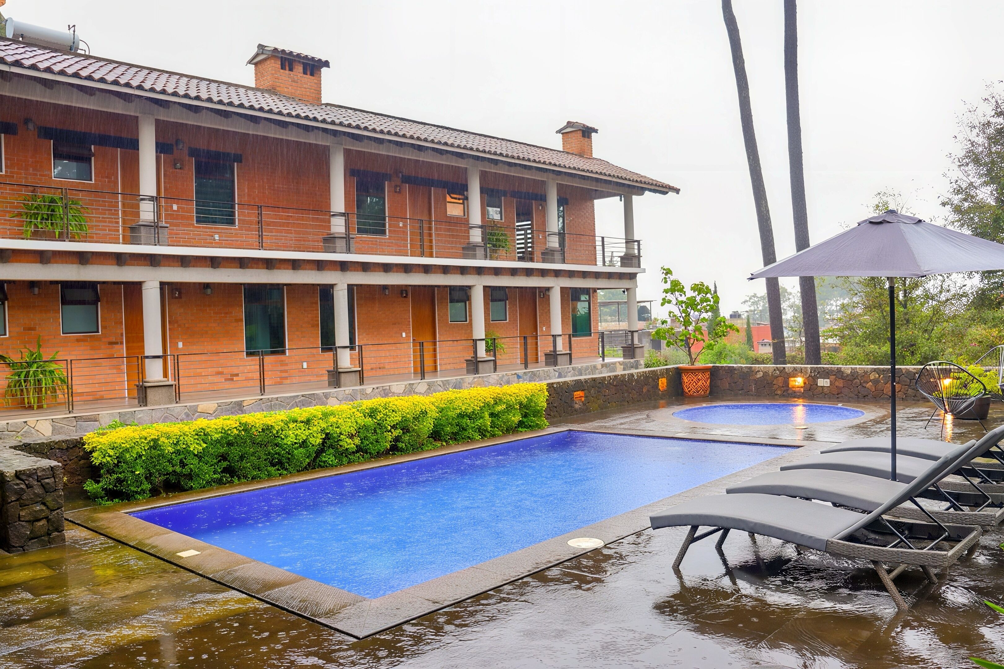 A two-story building with a swimming pool and lounge chairs.