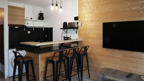 Et moderne køkken med en bar, træpaneler og et fladskærms-tv på væggen.