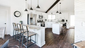 A modern kitchen with white cabinetry, a central island, and dark wood flooring. - Family Flagstaff Retreat  Sleeps 12 Mountain Views  EV Charger  Near NAU with AC (Flagstaff)