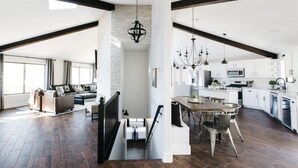 A spacious living area with a high ceiling, wooden beams, and a staircase leading to an upper level. - Family Flagstaff Retreat  Sleeps 12 Mountain Views  EV Charger  Near NAU with AC (Flagstaff)