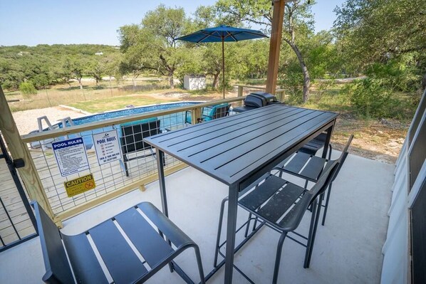A patio with a pool table, chairs, and a pool.