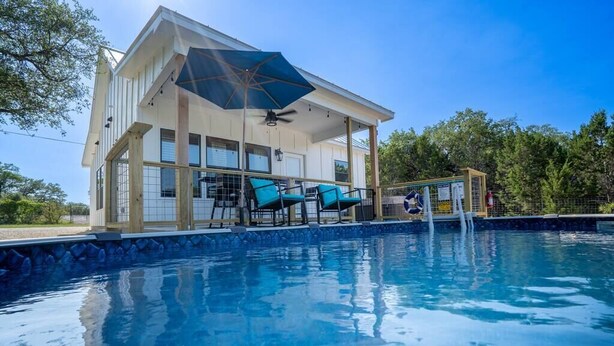 Zona junto a la piscina con área de descanso techada, piscina y deck de madera.