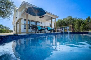A poolside area with a covered seating area, a pool, and a wooden deck.