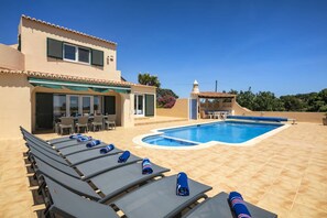 A poolside area with lounge chairs, a pool, and a building with a terrace. - Casa Vista Alta (Sleeps 8) Heatable pool, Lawn (Carvoeiro)