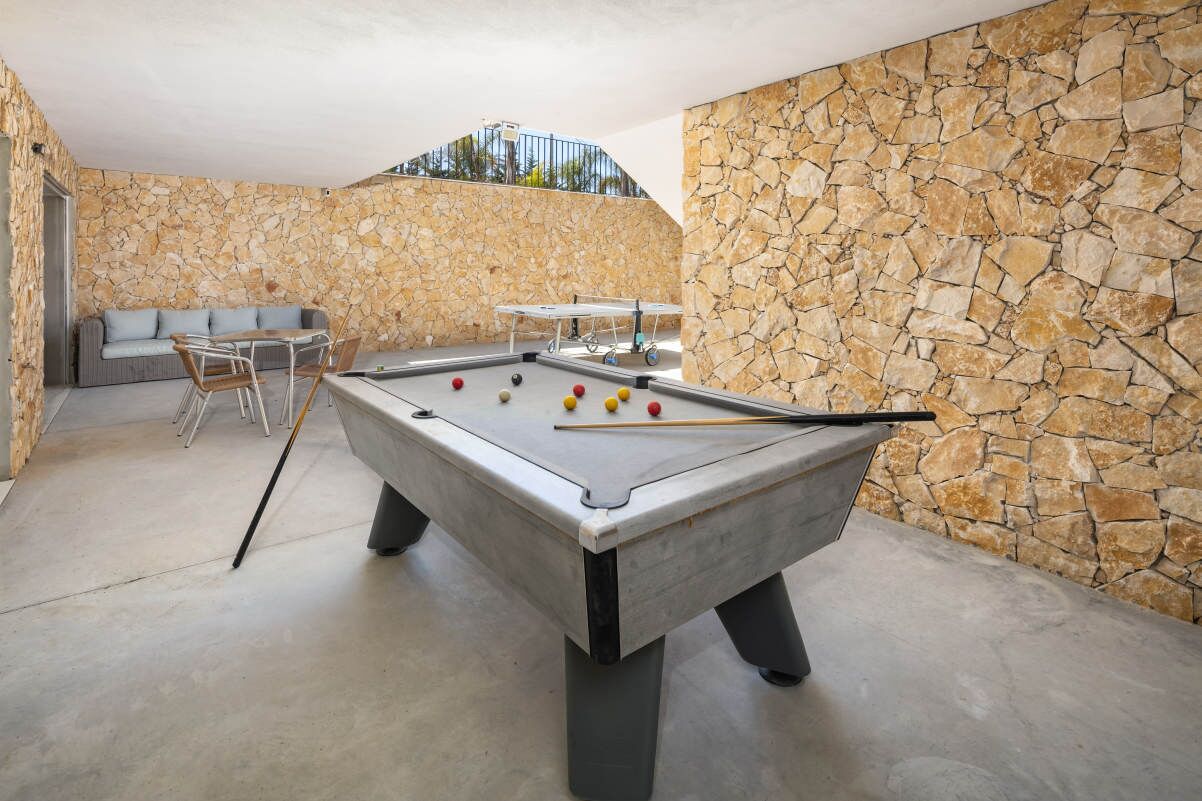 A pool table in a room with stone walls and a sofa.