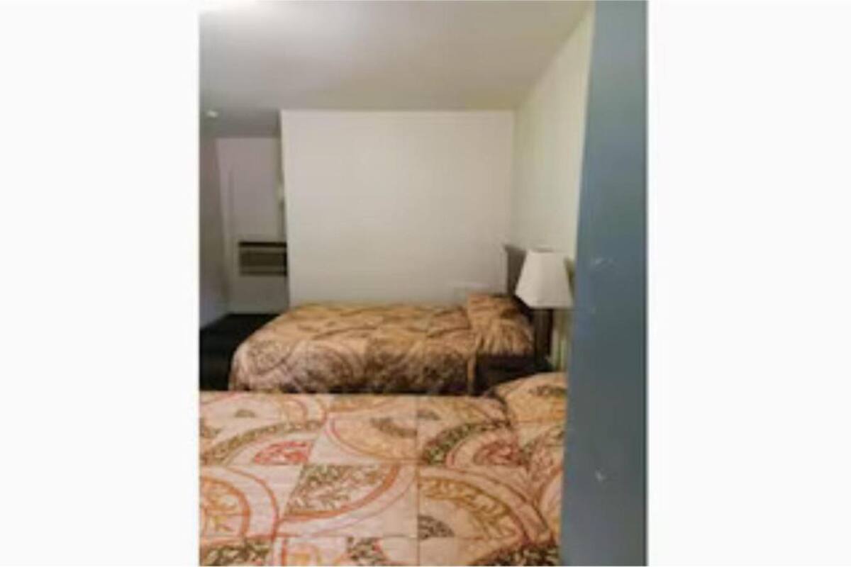 A hotel room with a bed, a nightstand, and a lamp.
