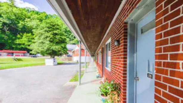 A red brick building with a covered porch and a blue door. - Travelers Inn by OYO Beaver, Hwy 19 (Beaver)