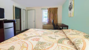 A bedroom with a bed, a desk, a television, and a window with curtains. - Travelers Inn by OYO Beaver, Hwy 19 (Beaver)