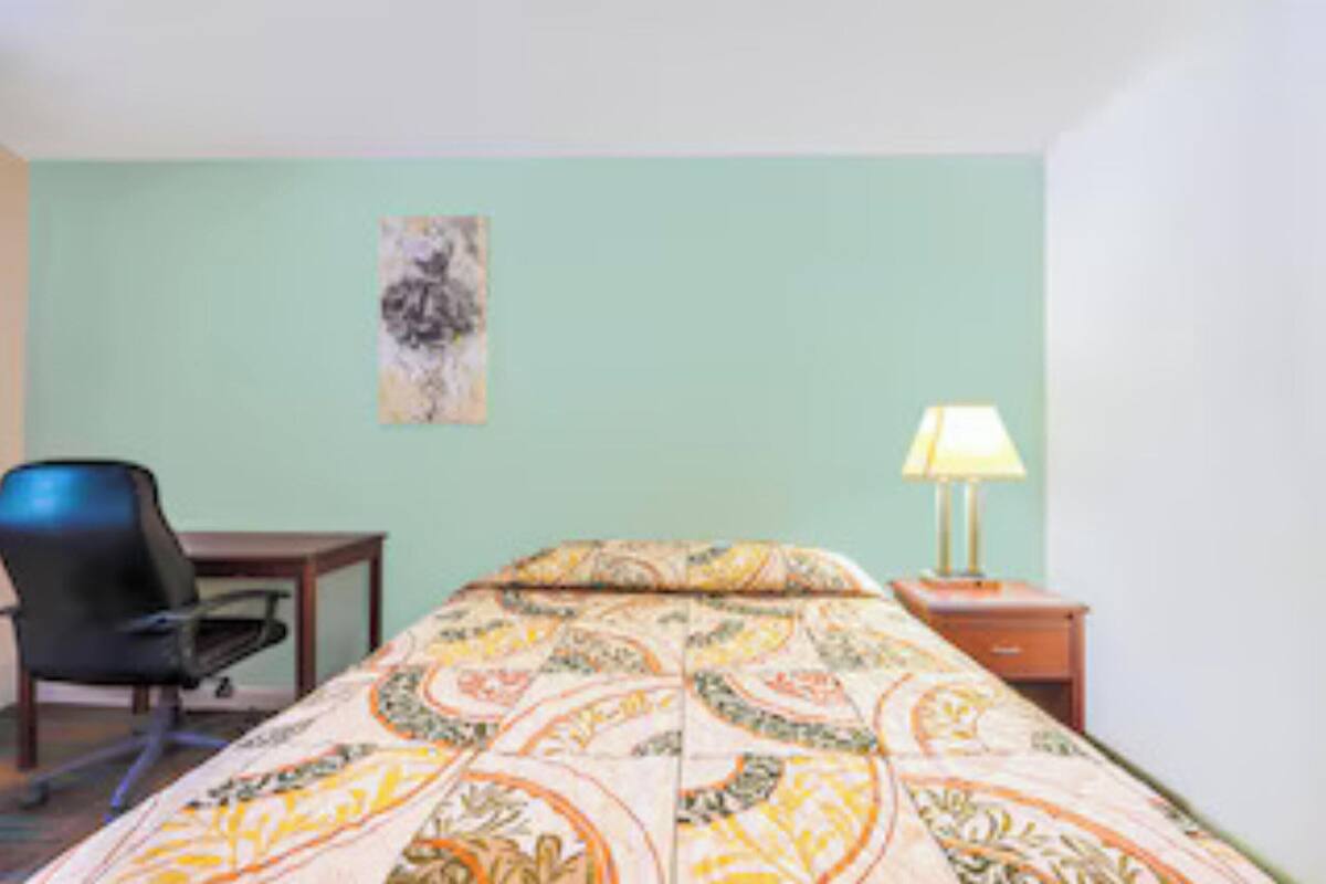 A room with a bed, a chair, a desk, and a lamp.